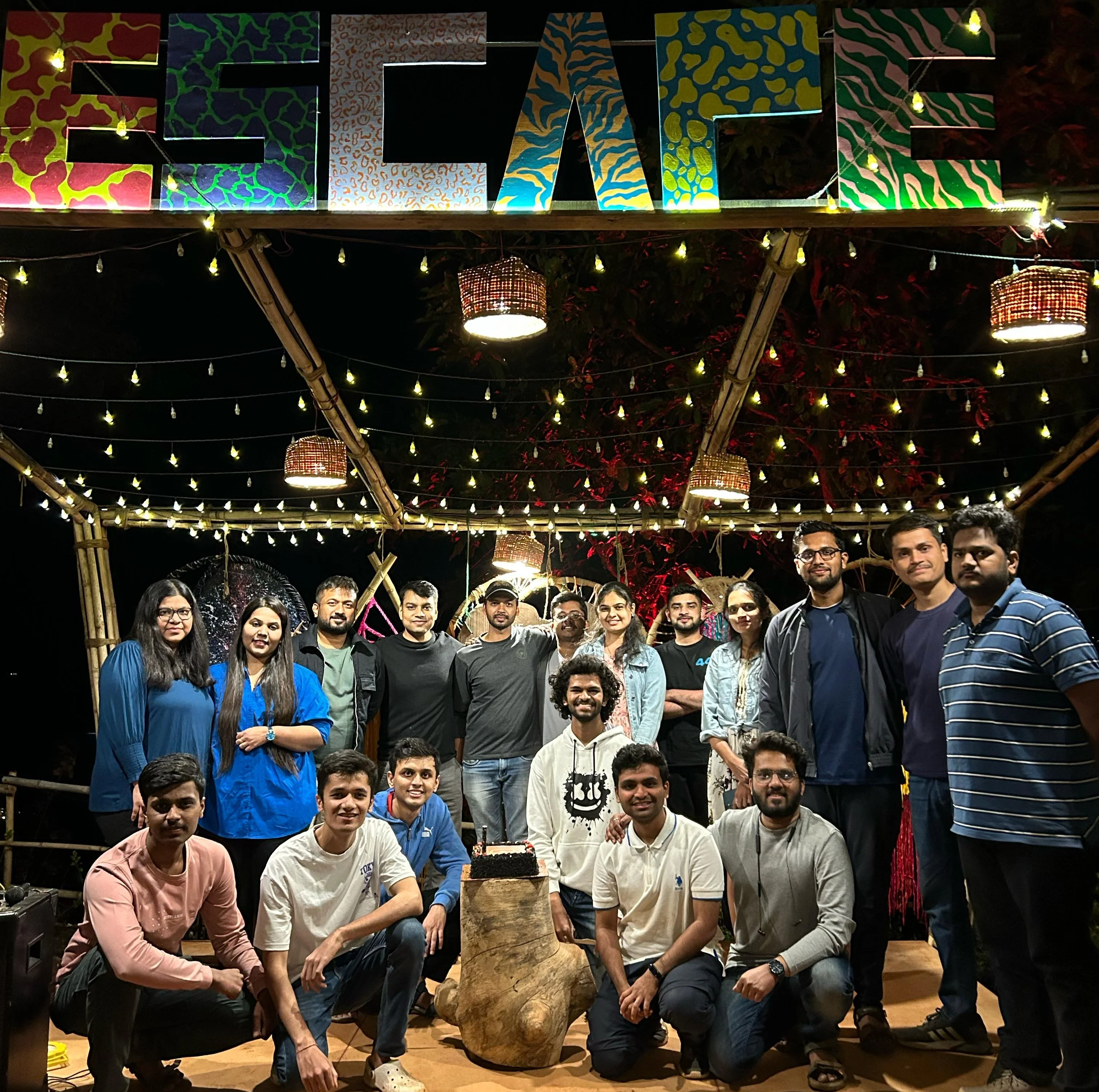 The team on an evening outing, under string lights and an Escape sign