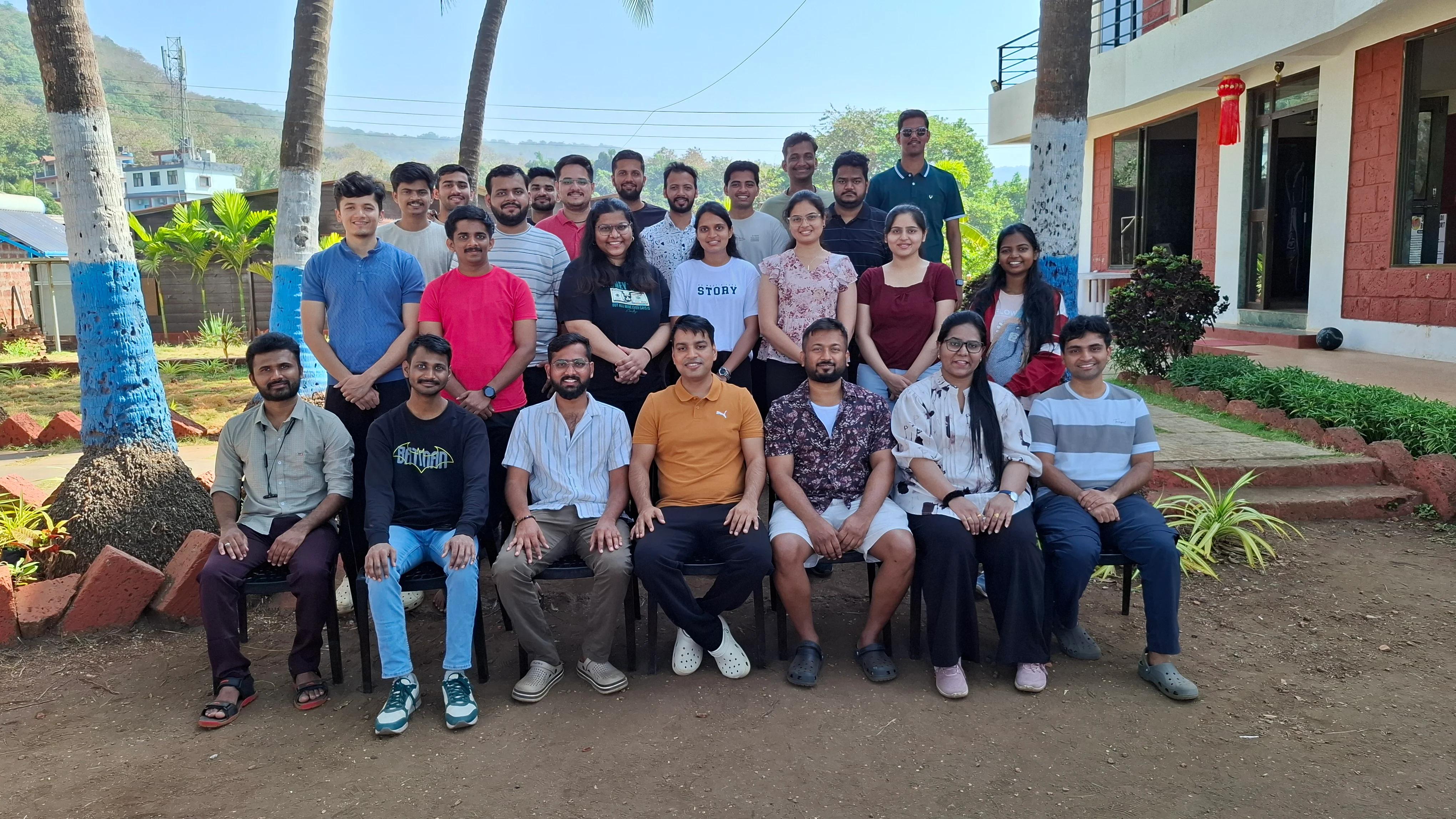 Team photo in front of a building among palm trees