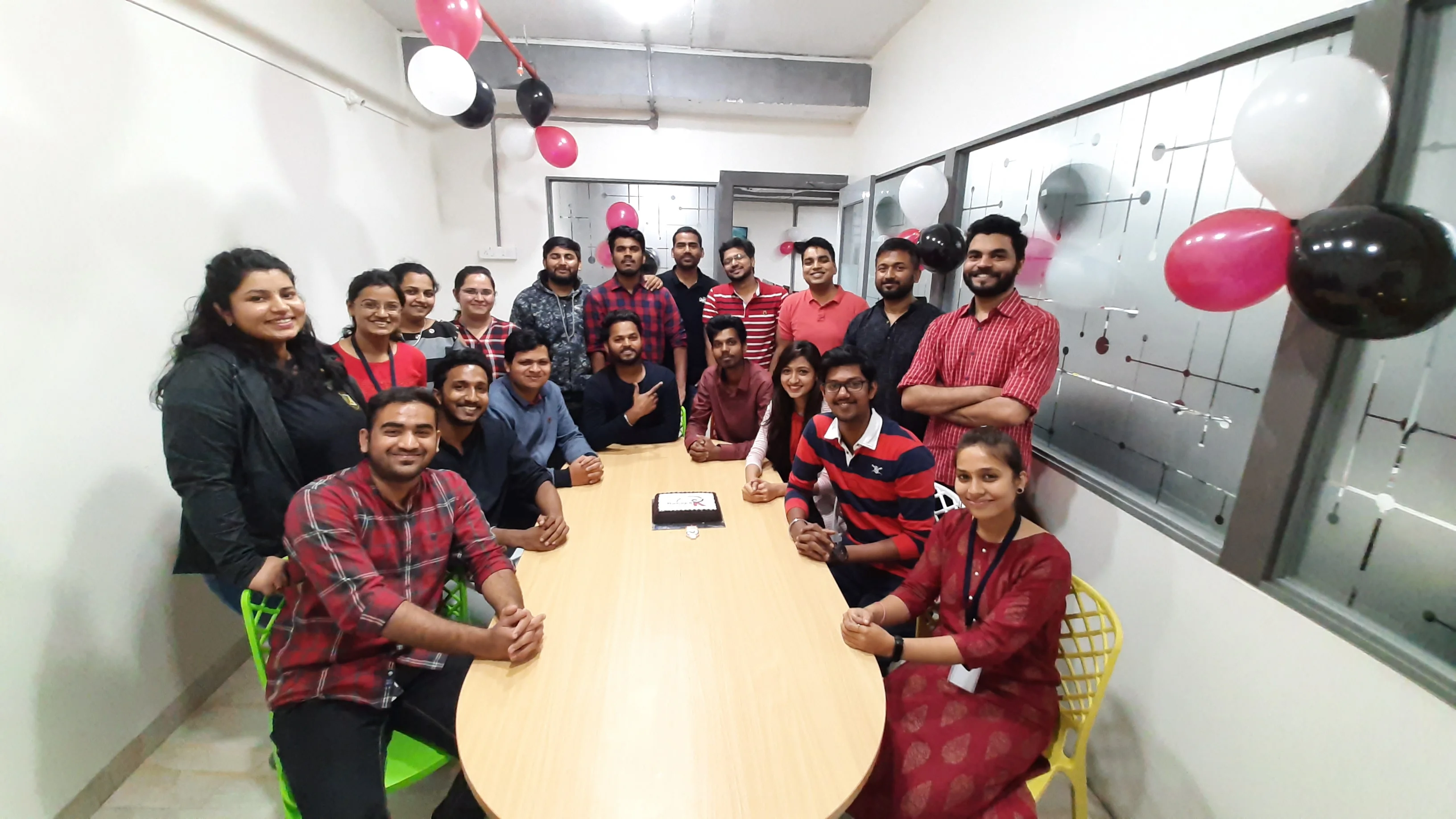 Colleagues around the meeting table at an office celebration with balloons